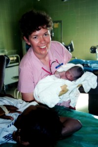 Pam holds baby boy she delivered in Dominican Republic as his Mom looks on.